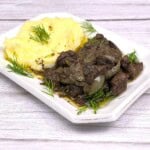 Chicken Livers With Onion Served on Square Plate With Mashed Potatoes