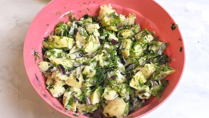 Tossing potato cubes, red onions, fresh herbs, and dried vegetable mix together.