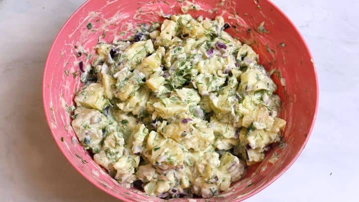 Finished potato salad with mayonnaise and sour cream fully assembled and creamy in a bowl.