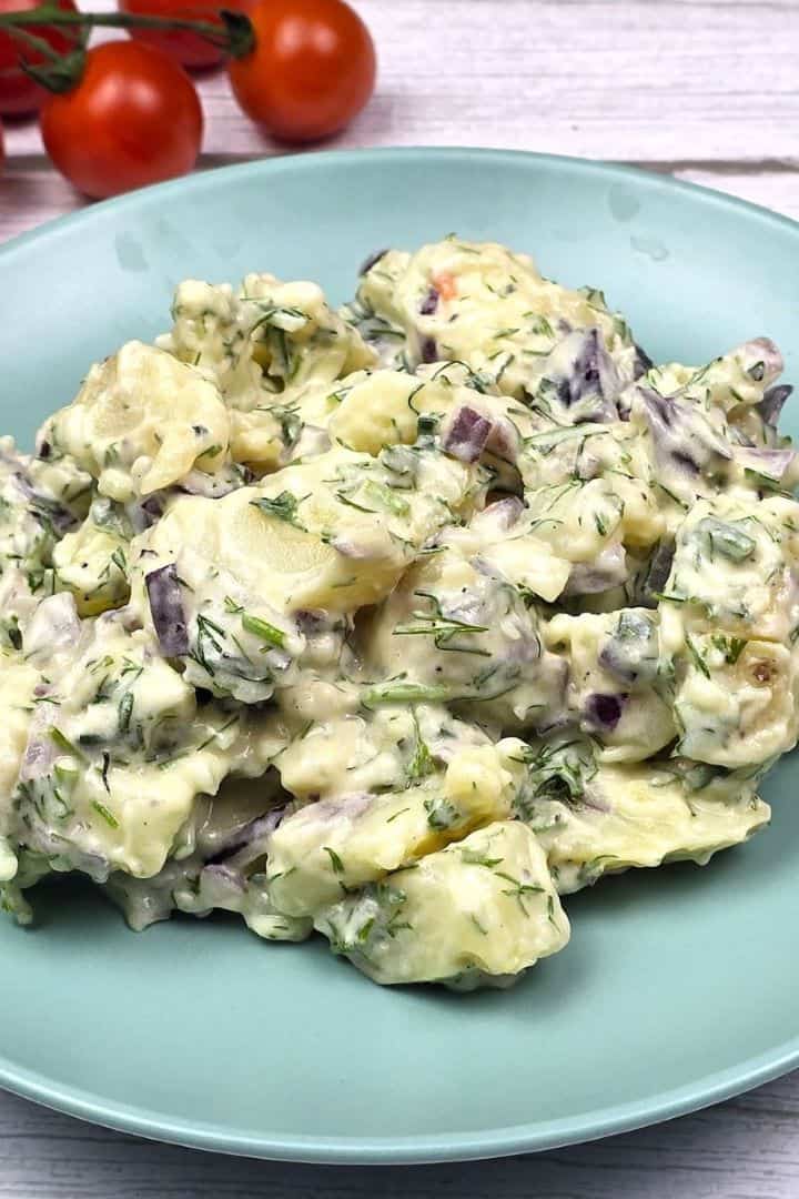 A serving of traditional potato salad with homemade mayonnaise dressing on a green plate.