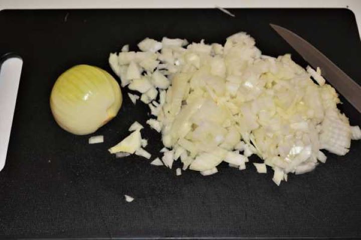 Cabbage Soup With Pork Meat-Chopped Onions Finely chopped white onions prepared on a black cutting board for a soup base.