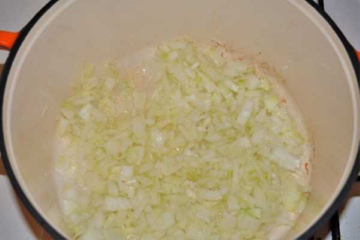 Cabbage Soup With Pork Meat-Frying Chopped Onions in the Pot Sautéing finely chopped white onions in sunflower oil inside a large Dutch oven soup pot.
