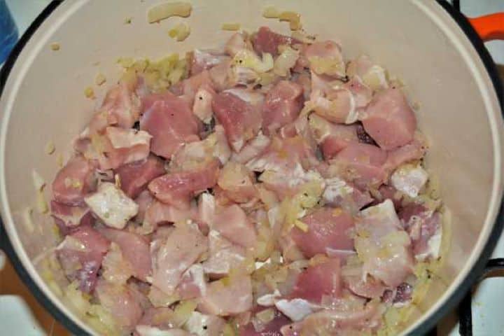 Cabbage Soup With Pork Meat-Frying Pork Meat Over the Chopped Onions in the Pot Adding diced pork shoulder cubes to the pot of sautéed onions.