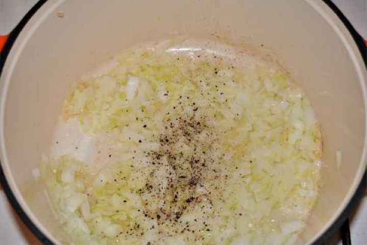 Cabbage Soup With Pork Meat-Seasoned Frying Chopped Onions in the Pot Chopped onions seasoned with ground caraway, salt, and black pepper cooking in a pot.
