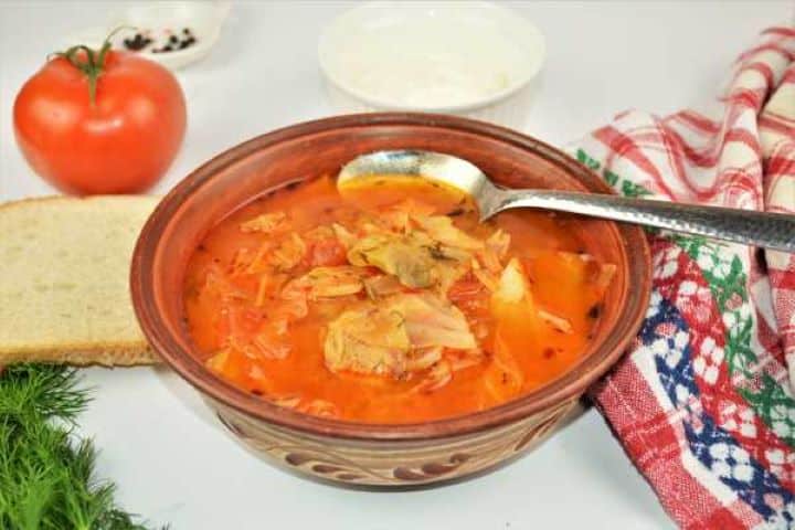 Cabbage Soup With Pork Meat-Served in Bowl With Fresh Bread Hungarian cabbage soup with pork meat served hot with a fresh green chili pepper and sliced bread on the side.