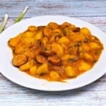 Hungarian Potato Stew With Smoked Sausage-Served on White Plate With Spring Onions