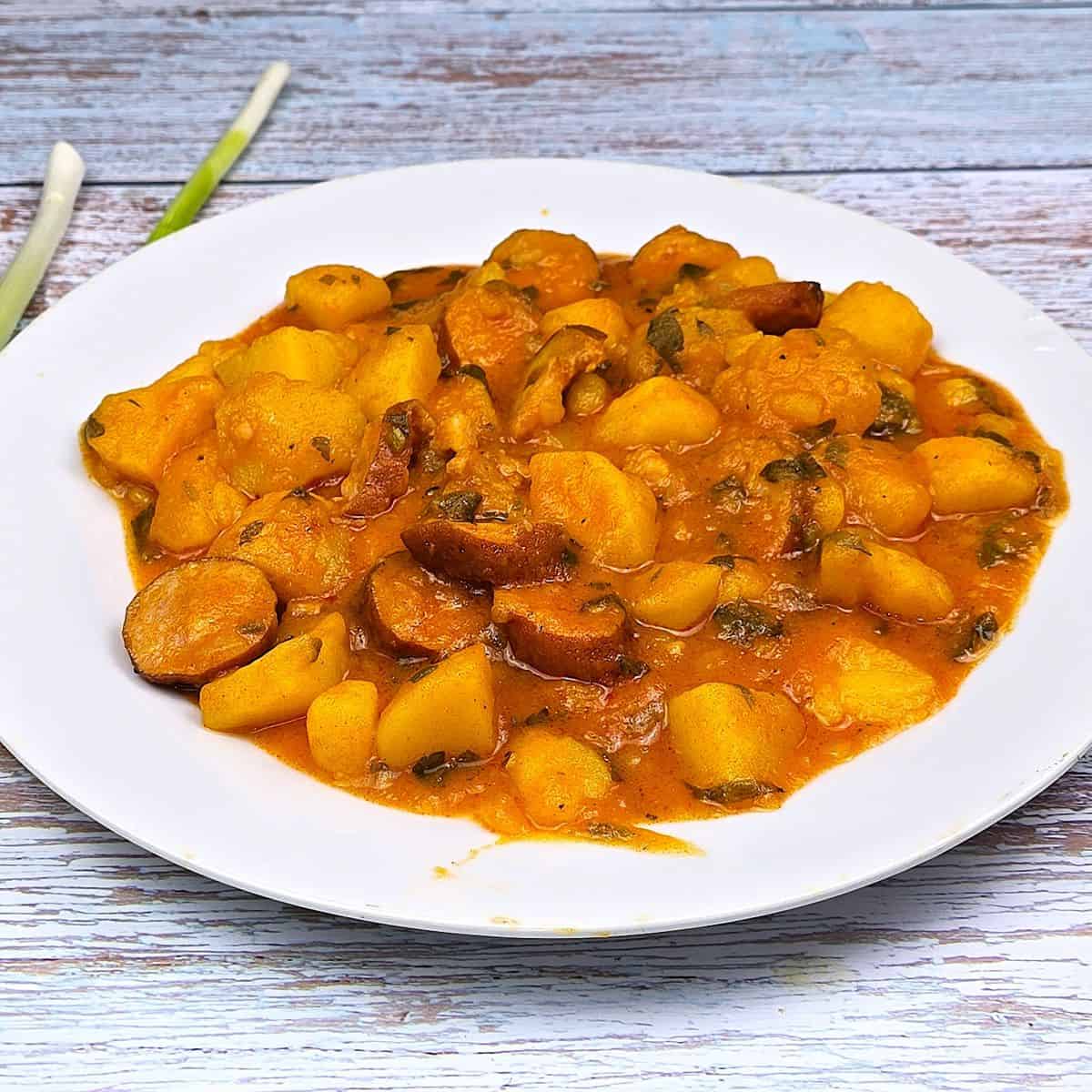 Hungarian Potato Stew With Smoked Sausage-Served on White Plate With Spring Onions
