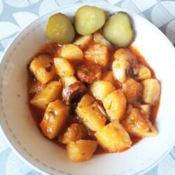 Potato stew with smoked sausages served with pickled cucumber