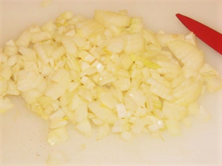 Chopped onion Finely diced white onions on a white cutting board, prepped for cooking the soup base.