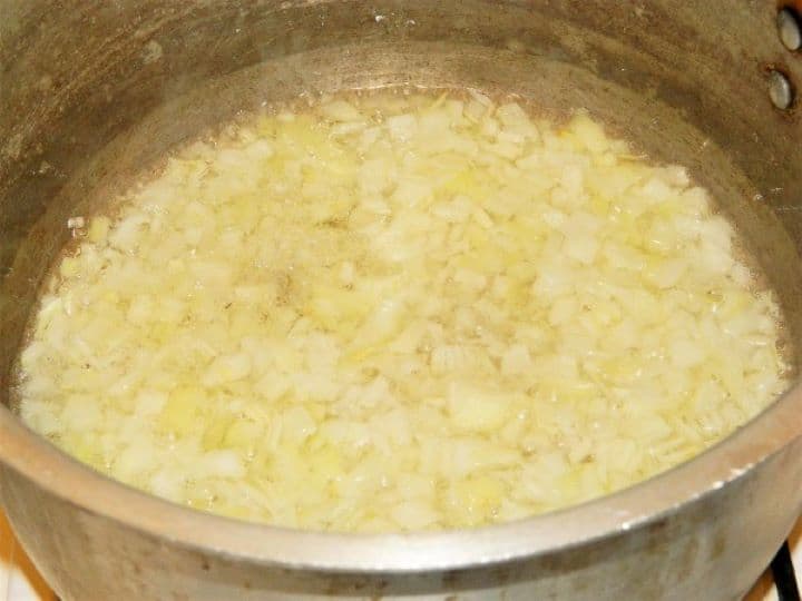 Frying chopped onions Sautéing finely chopped onions in sunflower oil inside a large soup pot until soft and translucent.