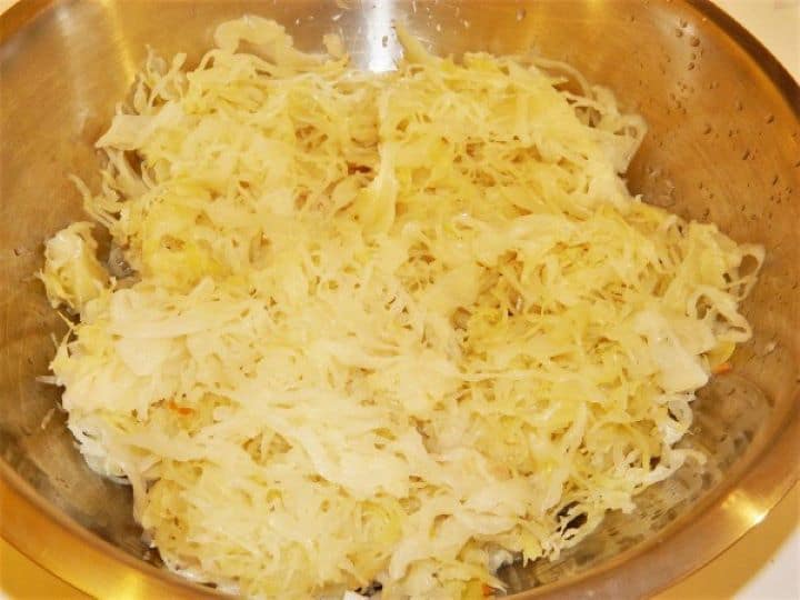 Sauerkraut Finely shredded raw sauerkraut packed in natural brine inside a sieve, ready to be rinsed for the recipe.