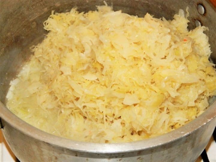 Frying sauerkraut Stirring the shredded sauerkraut into the pot with the sautéed onions to build the soup base flavors.