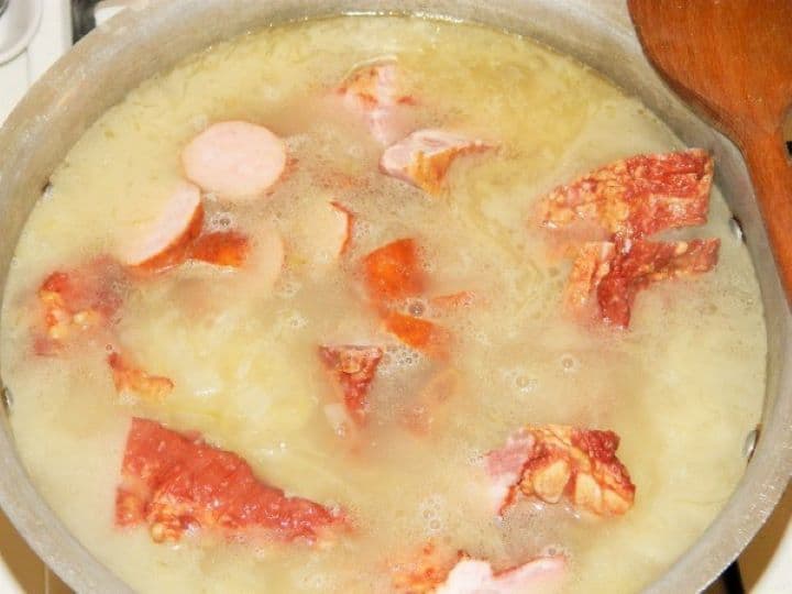 Smoked ribs and sliced sausage in the pot Adding the cut smoked pork ribs and sliced smoked sausages into the boiling cabbage soup broth.