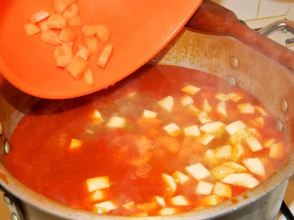 Traditional Hungarian Goulash Recipe-Adding Cut Carrots and Parsley Roots to Boiling Goulash