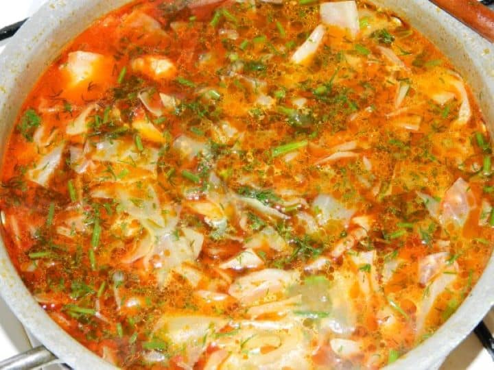 Stirring fresh chopped dill into the boiling cabbage and tomato soup broth.