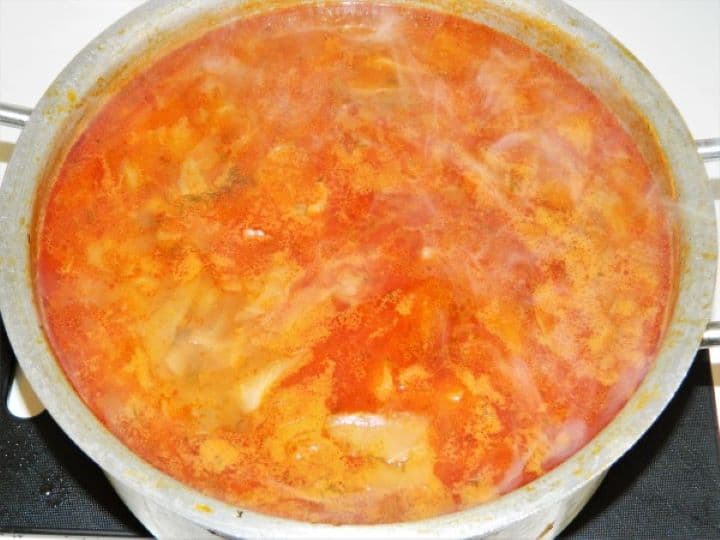 A large pot of freshly thickened traditional Hungarian cabbage soup showing a rich, velvety crimson broth.