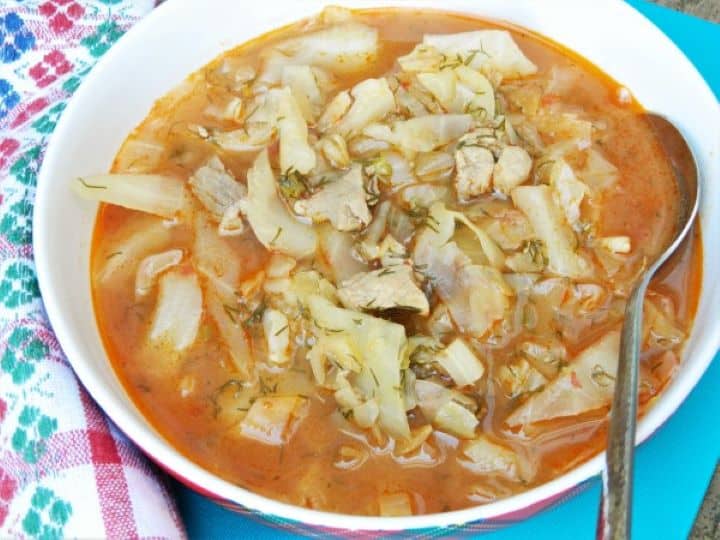 A steaming bowl of old-school Hungarian cabbage soup with tender pork shoulder and fresh dill, ready to eat.