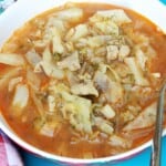 Traditional Hungarian cabbage soup called Lucskos Kaposzta served hot in a rustic ceramic bowl with sour cream and crusty bread.