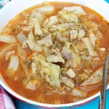 Traditional Hungarian cabbage soup called Lucskos Kaposzta served hot in a rustic ceramic bowl with sour cream and crusty bread.