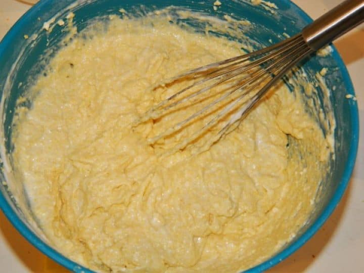 Gently folding egg white foam into the cornbread dough with a whisk.