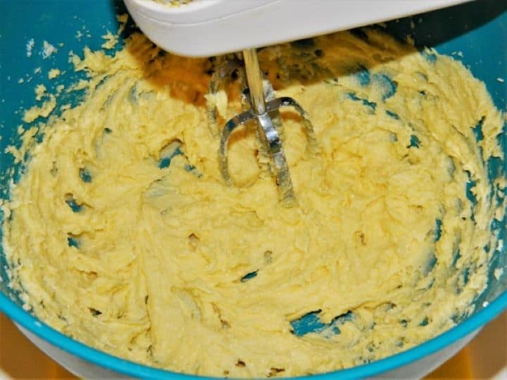 Beating butter, egg yolks, and sugar with a hand mixer.