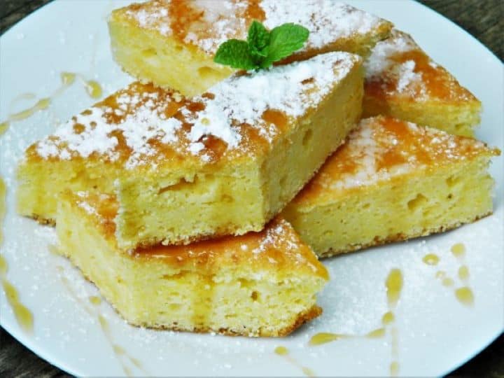 Sweet cornbread with cottage cheese served on white plate with honey.