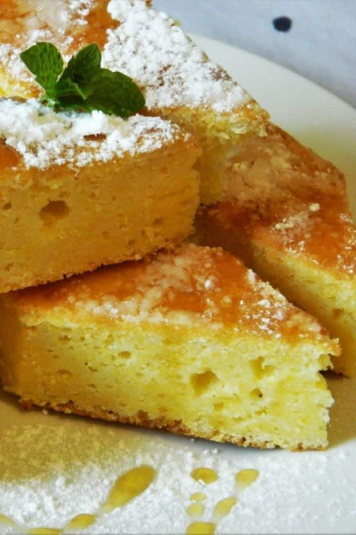 Slice of sweet cornbread with cottage cheese drizzled with honey on a white plate.