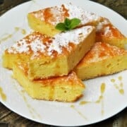 Slice of sweet cornbread with cottage cheese drizzled with honey on a white plate.