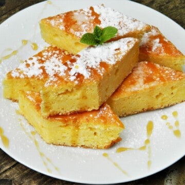 Slice of sweet cornbread with cottage cheese drizzled with honey on a white plate.