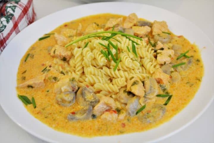Best Turkey Stew Recipe-Served on Plate With Pasta Velvet-smooth, rich turkey paprikash with mushrooms being ladled over a steaming bowl of spiral fusilli pasta.