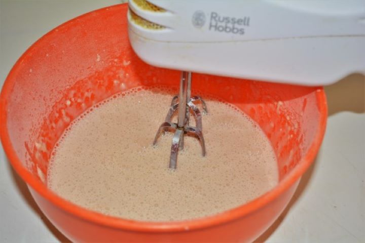 Easy Cinnamon Apple Pancakes Recipe-Mixing the Ingredients With a Hand Mixer Mixing homemade pancake batter with a hand mixer in a glass bowl, with ground cinnamon, vanilla sugar, and fresh grated apples being folded in.