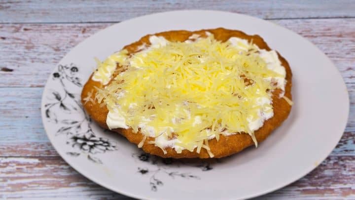 Homemade Fried Dough Recipe-Served With Sour Cream and Grated Cheese Authentic Hungarian Lángos Served on White Plate With Sour Cream and Grated Cheese