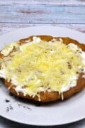 Authentic Hungarian Lángos Served on Plate With Sour Cream and Grated Cheese on Top