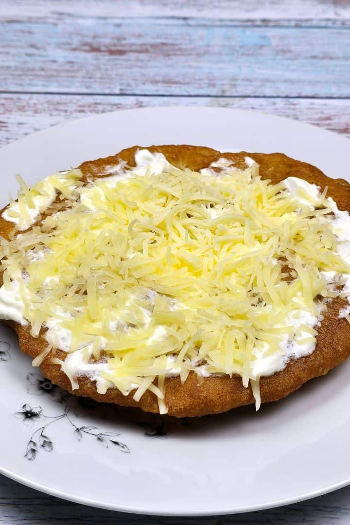 Authentic Hungarian Lángos Served on Plate With Sour Cream and Grated Cheese