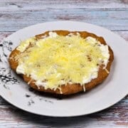 Authentic Hungarian Lángos Served on Plate With Sour Cream and Grated Cheese