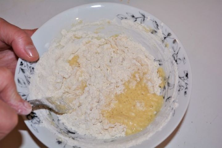 Whisking eggs, flour, and water with a fork in a small bowl to make traditional Hungarian drop dumpling batter.