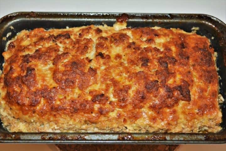 A freshly baked whole Hungarian Stefánia szelet pork meatloaf with a crispy, unglazed golden crust in a loaf pan.