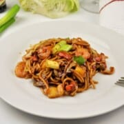15-minute king prawn noodles recipe with teriyaki sauce and egg noodles on a white plate