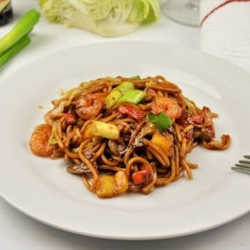 15-minute king prawn noodles recipe with teriyaki sauce and egg noodles on a white plate