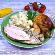 A golden-brown crispy baked stuffed whole chicken on a green serving platter with potatoes, sliced to reveal the traditional Transylvanian bread stuffing.