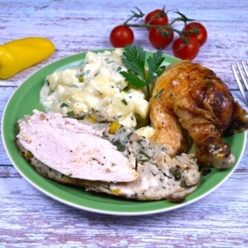 A golden-brown crispy baked stuffed whole chicken on a green serving platter with potatoes, sliced to reveal the traditional Transylvanian bread stuffing.