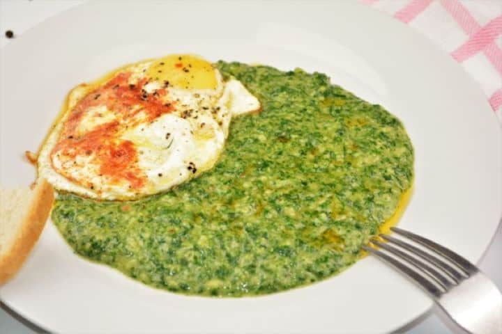 Quick Creamed Spinach Recipe Served on White Plate With Fried Egg and a Slice of Bread