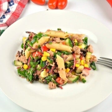 A beautifully plated portion of healthy tuna pasta salad without mayo, showing a colorful mix of penne, sweetcorn, crisp red bell pepper, and fresh chives.