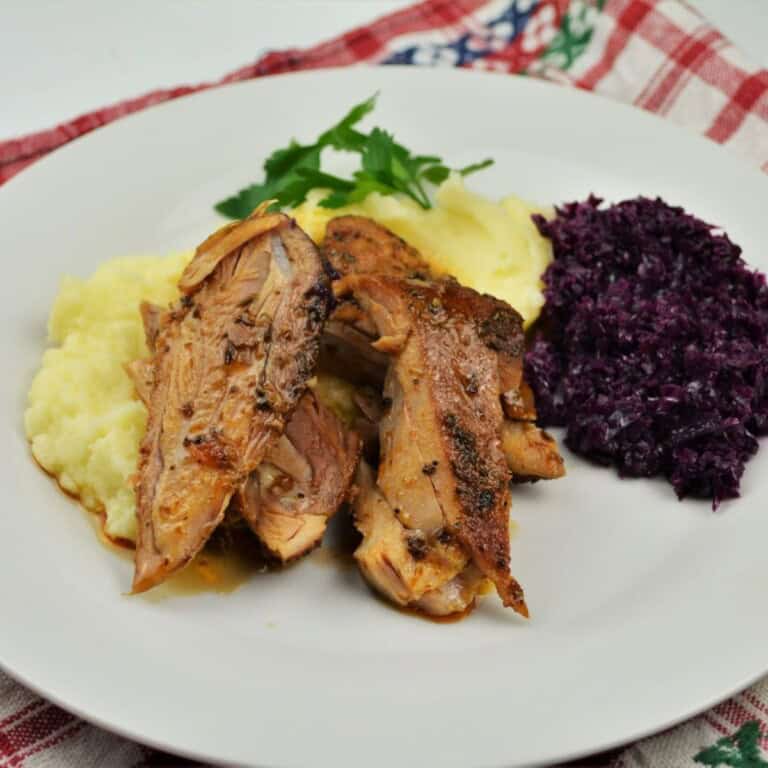 Oven Baked Turkey Legs Served on White Plate With Mashed Potatoes and Red Cabbage