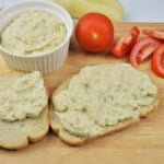 A thick layer of smoky Romanian eggplant dip spread on a slice of crusty rustic bread.
