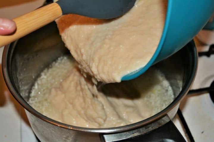 Easy Homemade Refried Beans Recipe-Pouring Mashed White Beans in the Pot Pouring Mashed White Beans in the Pot Over the Garlic