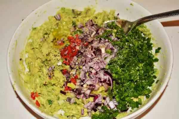 Best Homemade Guacamole Recipe-Seasoned Chopped Chives, Red Onion and Chilli Pepper Over the Mashed Avocados