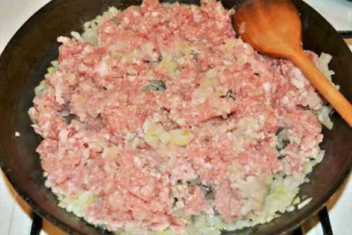Easy Potato Moussaka Recipe-Frying Pork Mince With Chopped Onions in the Pan Browning minced pork with sautéed onions in a skillet for musaca de cartofi.