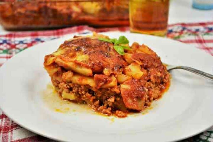 Easy Potato Moussaka Recipe-Served on Plate With a Fork Warm square slice of layered Romanian potato moussaka served on a dinner plate with a fork.