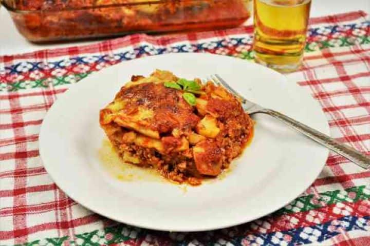 Easy Potato Moussaka Recipe-Served on Plate With a Fork Overhead view of a hearty slice of baked musaca de cartofi served with a fork on a rustic table.